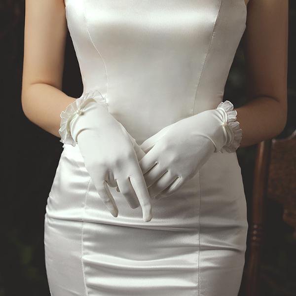 Delicate white bridal gloves with lace edges