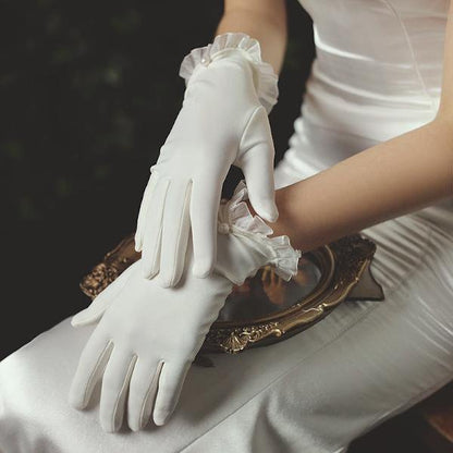 Delicate white bridal gloves with lace edges