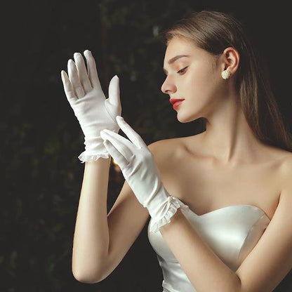 Delicate white bridal gloves with lace edges